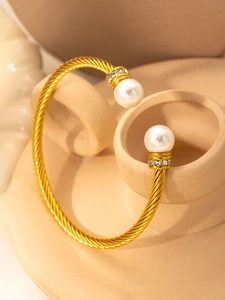 Close-up of gold cable bangle featuring dual white pearls and micro-pave crystals