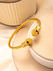Detailed shot of gold skull cable wire bracelet with punk twisted stainless steel texture
