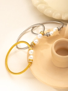Detail of twisted cable bangles in gold and silver with large pearls and crystal spacers