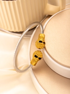 Detailed macro view of woven steel cable bracelet with gold skull heads in punk style