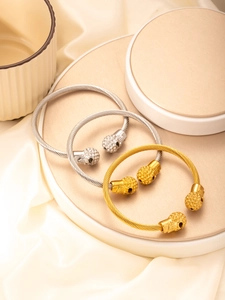 Detail of twisted cable bracelets with skull ends in gold and silver finish