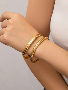 Close-up of gold star bangle with crystals on wrist against a neutral wall