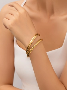 Detail of two gold-plated star engraved bangles with zircon crystals on woman's wrist