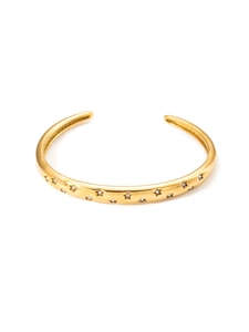 Macro detail of gold cuff bracelet featuring star engravings and sparkling zircons