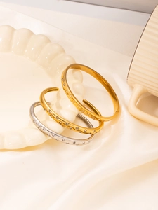 Detailed view of three-piece star engraved titanium steel bracelets on beige satin fabric