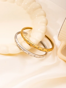 Detailed view of gold and silver star bangles with crystals on a ceramic tray