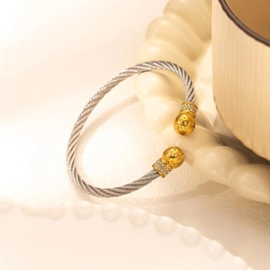 Gold cable twist bangle with rhinestone studded spheres in polished stainless steel