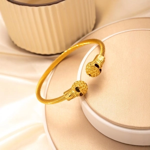 Punk style gold cable wire bangle featuring detailed skull heads at both ends