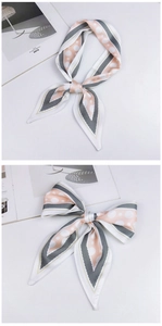 Detailed close-up of pink polka dot silk scarf tied in a bow on a minimalist magazine