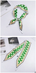 Close-up of green polka dot skinny silk scarf and twilly tied on an art magazine