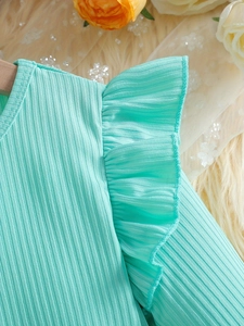 Close-up of mint green ribbed fabric with ruffle detail on long sleeve girl dress