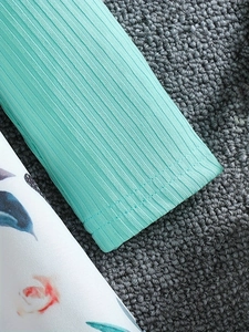 Detail of mint green ribbed knit fabric with floral print stitching and neat hem