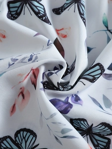 Detailed macro view of soft twill floral fabric featuring blue butterfly and leaf prints
