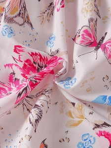 Dettaglio macro del tessuto con stampa di fiori e farfalle su abito estivo da bambina