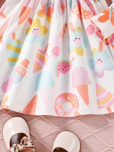 Detail eines Baby Mädchen Kleides mit Eiscreme-Print und weißen Lacklederschuhen