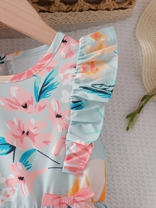Close-up of floral girls dress with ruffle sleeves and a pink checkered waist bow