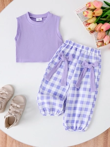 Flat lay of girl's purple ribbed vest and checkered pants with bow detail and sandals