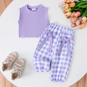 Flat lay of baby girls purple ribbed tank top and checkered bow pants with summer sandals