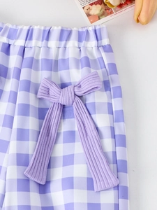 Detail of girls' purple plaid pants featuring an elastic waist and a large ribbed bow