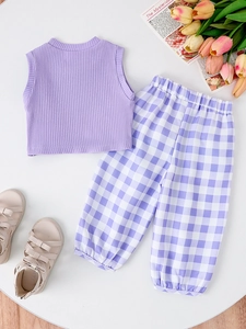 Flat lay of purple ribbed tank top and checkered trousers for girls with summer props