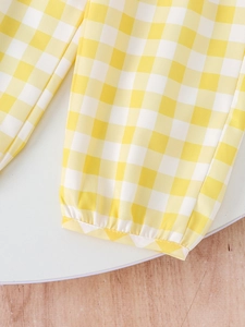 Detail of yellow and white plaid trousers featuring an elasticated hem for a snug fit