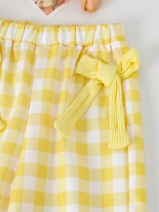 Detail of yellow checkered pants with elastic waist and large decorative bow for girls