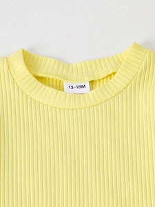 Detail of yellow ribbed knit toddler top with size label 12-18M and clean stitching