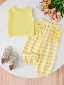 Flat lay of girl's yellow ribbed vest and plaid pants set with size label 12-18M