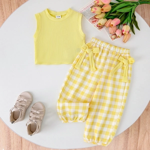 Close-up of girls' yellow ribbed tank top and checkered pants with bow details