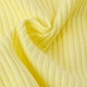Close-up of pale yellow ribbed fabric texture showing soft pleats and wavy knit details