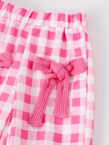 Detail of pink gingham fabric with a ribbed bow decoration and elastic waistband