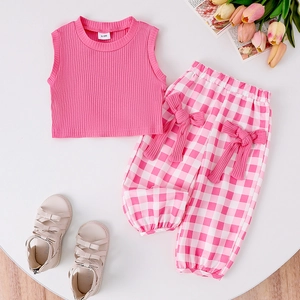 Close-up of baby girl pink ribbed tank top and checkered pants with bow details