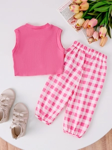 Flat lay of pink knit tank top and pink checkered trousers with a cute bow detail