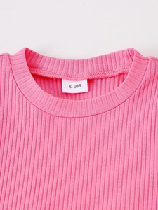 Macro shot of pink ribbed knit baby bodysuit neckline and 6-9M size label detail