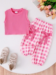 Close-up of pink sleeveless top and checkered pants with bow for baby girls