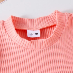 Close-up of pink ribbed knit baby top neckline with 12-18M size label detail