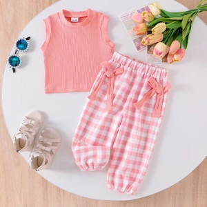 Flat lay of baby girl pink ribbed tank top and plaid trousers with bow tie details