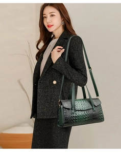 Détail de texture crocodile vert foncé sur un sac à main avec des finitions dorées