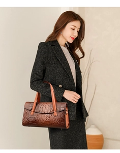 Détail du sac à main motif crocodile avec poignée orange porté sur un tailleur chic
