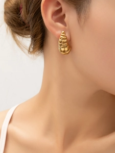 Vue rapprochée de boucles d'oreilles spirale plaquées or 18 carats portées par un mannequin