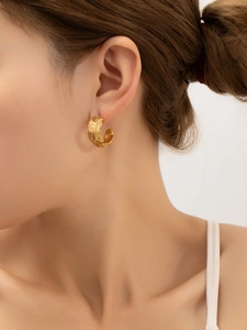 Gros plan de boucles d'oreilles dorées en C avec texture plume sur modèle