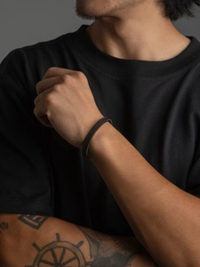 Detailed view of men's matte black woven stainless steel mesh cuff bracelet worn on wrist