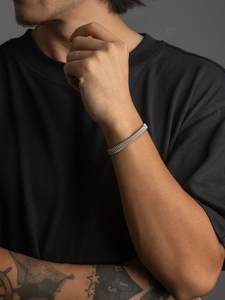 Close-up of silver braided stainless steel C-shaped cuff bracelet on male model's wrist