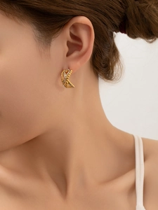 Gros plan de boucles d'oreilles entrelacées plaquées or 18k avec zircons sur modèle