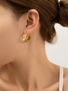 Détail d'une boucle d'oreille C en plaqué or 18k avec texture lave et perle blanche