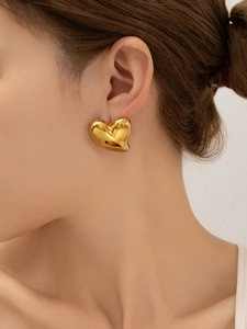 Gros plan de boucles d'oreilles cœur 3D plaquées or 18 carats portées par un mannequin