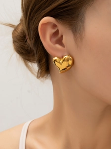Gros plan d'une boucle d'oreille cœur plaquée or 18 carats portée par un mannequin
