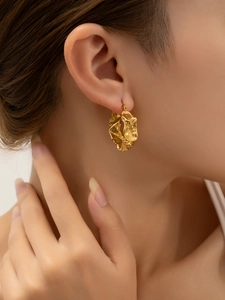 Gros plan détaillé des boucles d'oreilles en C plaquées or 18 carats avec texture lave