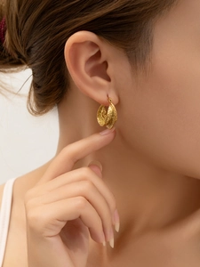 Gros plan de boucles d'oreilles en C plaqué or 18 carats avec texture martelée