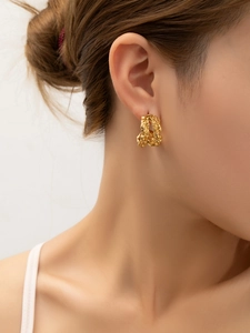 Détail de boucles d'oreilles C dorées avec texture lave et plaqué or 18 carats